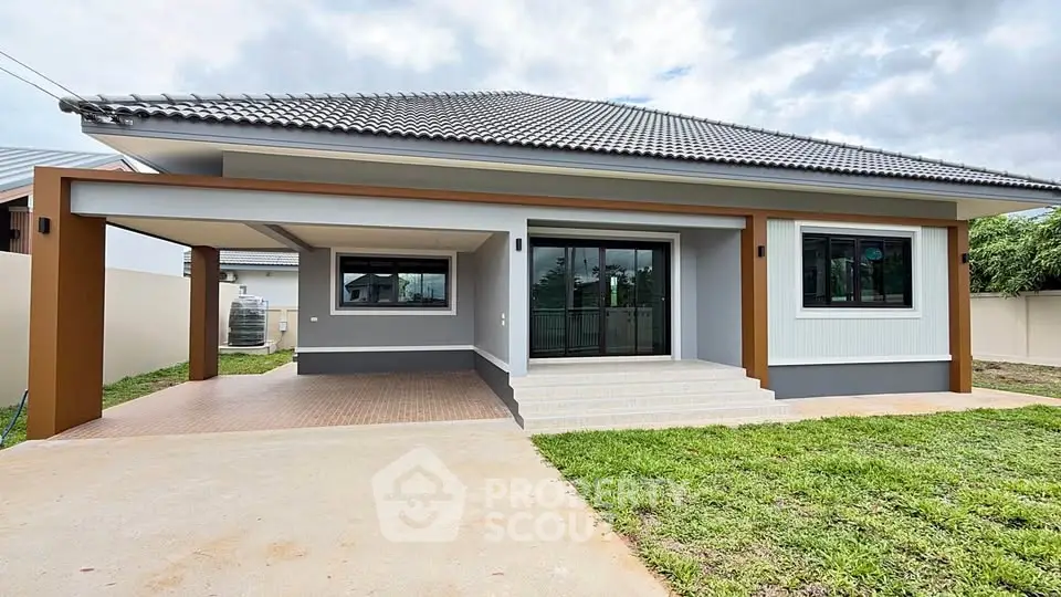 Modern single-story house with spacious driveway and lush green lawn, featuring sleek architectural design and large windows.