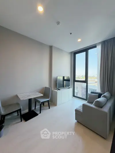 Modern living room with large window and cozy seating area in a high-rise apartment.