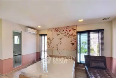 Spacious bedroom with artistic wall design and large windows for natural light.