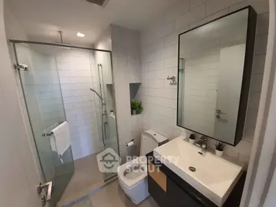 Modern bathroom with glass shower, sleek vanity, and contemporary fixtures.