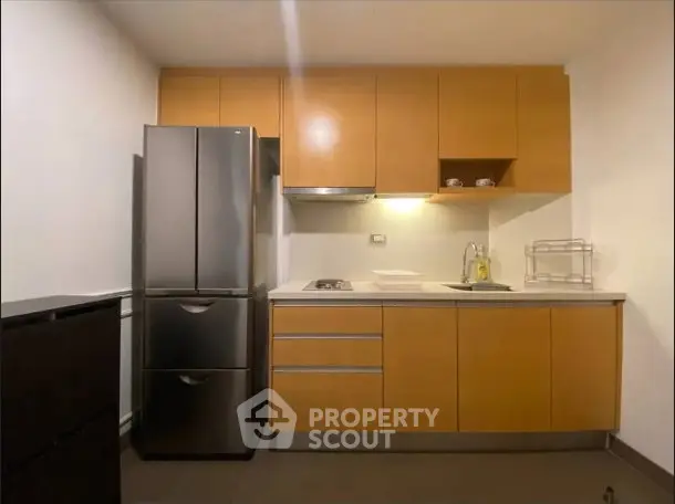 Modern kitchen with sleek cabinetry and stainless steel fridge in a compact layout.
