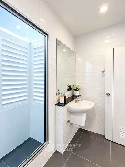 Modern bathroom with sleek white tiles and large window for natural light.