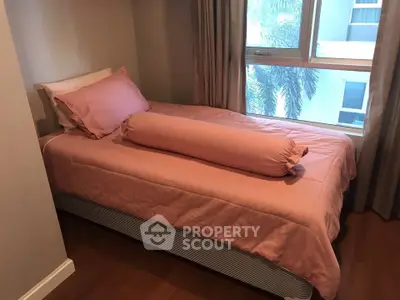 Cozy bedroom with pink bedding and large window offering natural light