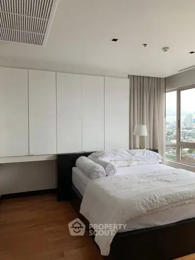 Modern bedroom with city view, featuring sleek design and natural light.