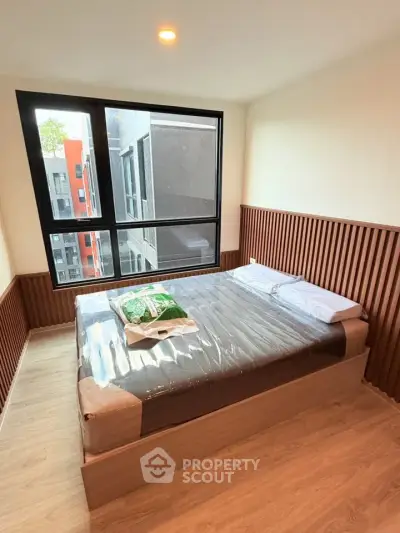 Modern bedroom with large window and stylish wood paneling in urban apartment