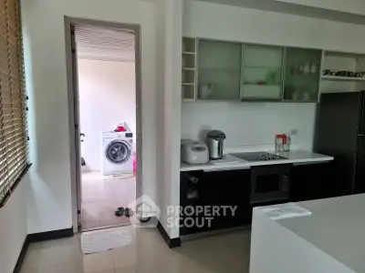 Modern kitchen with sleek appliances and adjacent laundry area in a stylish home.