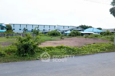 Vacant land plot with potential for development, surrounded by greenery and nearby buildings.