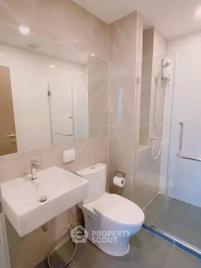 Modern bathroom with sleek fixtures and glass shower enclosure in contemporary apartment.