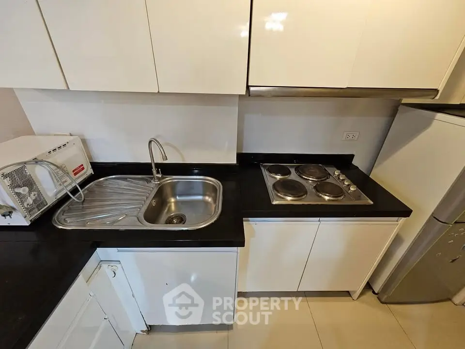 Modern compact kitchen with sleek cabinets, stainless steel sink, and electric stove.