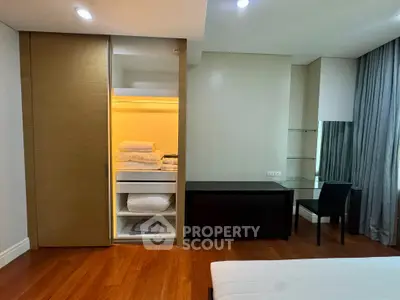 Spacious bedroom with built-in closet and study desk, featuring elegant wooden flooring and modern lighting.