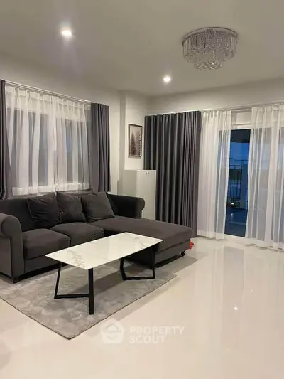Elegant living room with modern sofa, marble coffee table, and chic curtains.