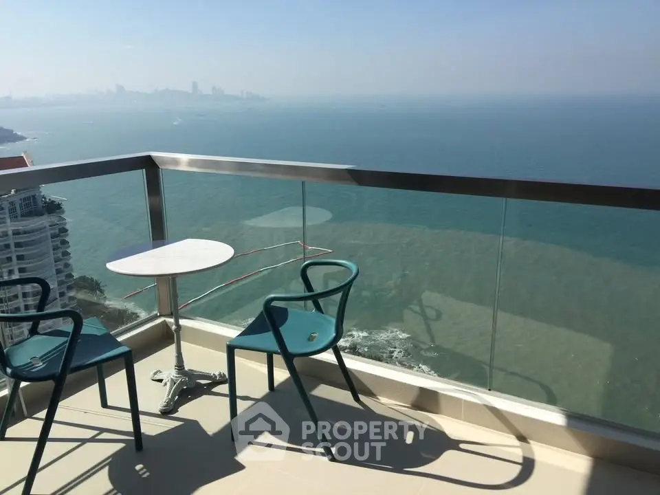 Stunning ocean view from a high-rise balcony with modern seating, perfect for relaxation.