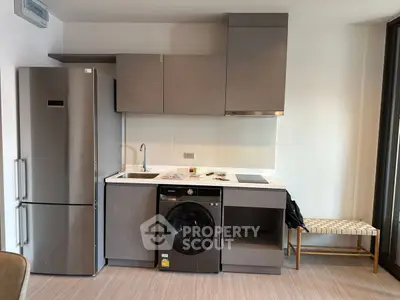Modern kitchen with sleek appliances and compact design, featuring a washing machine and fridge.