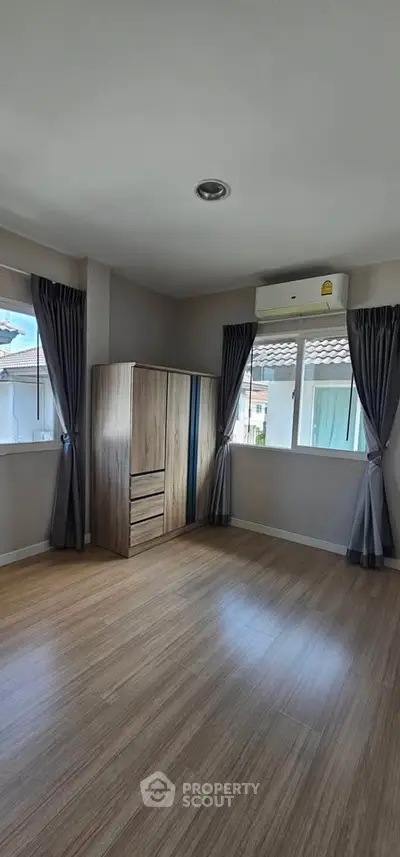 Spacious bedroom with wooden flooring and ample natural light