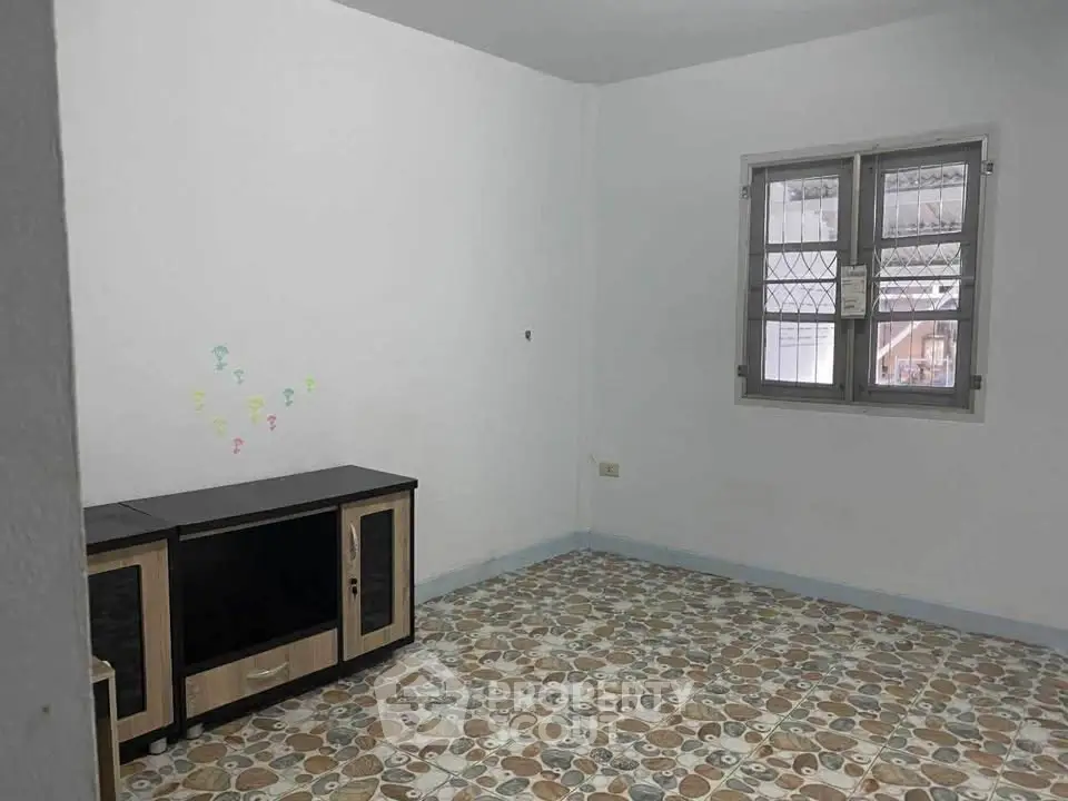 Spacious unfurnished room with tiled flooring and a window, ideal for customization.