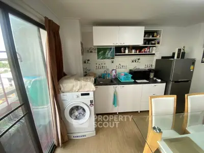 Cozy kitchen with washing machine and modern appliances, perfect for compact living.