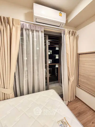 Cozy bedroom with balcony access and air conditioning in modern apartment.