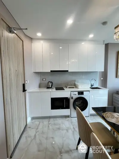 Modern kitchen with sleek white cabinets, built-in appliances, and elegant dining area