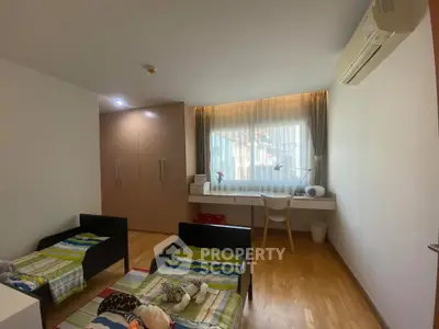 Spacious bedroom with twin beds, large window, and built-in wardrobe