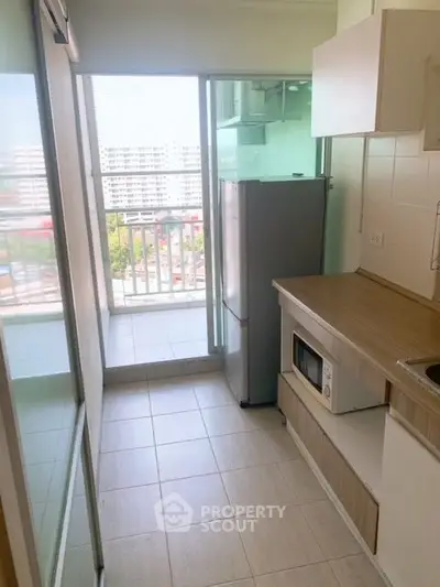 Modern kitchen with balcony view, featuring sleek appliances and ample natural light.