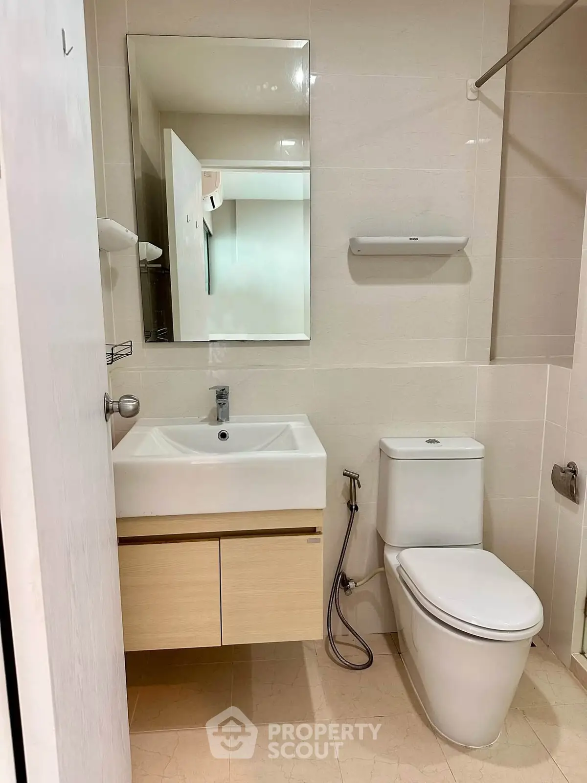 Modern bathroom with sleek fixtures and neutral tones, featuring a wall-mounted sink and toilet.