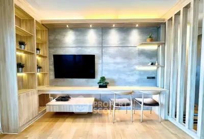 Modern living room with sleek wooden furniture and built-in shelving, featuring a wall-mounted TV and stylish lighting.