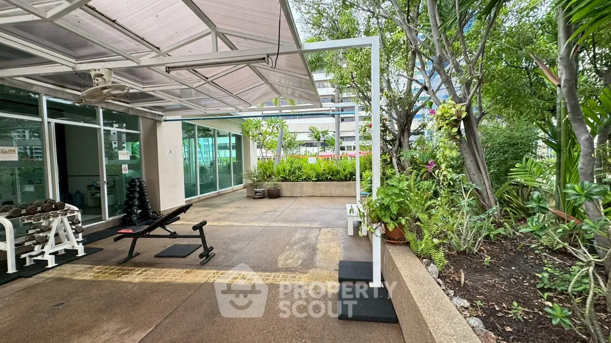 Outdoor gym area with lush greenery and modern equipment in a residential complex.