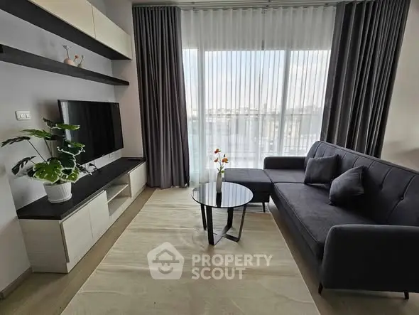 Modern living room with sleek furniture and large window offering natural light.