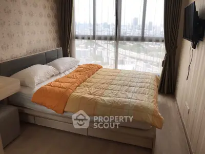 Cozy bedroom with city view and modern decor in high-rise apartment.