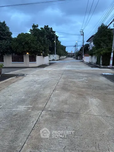Quiet residential street with trees and houses, perfect for serene living.