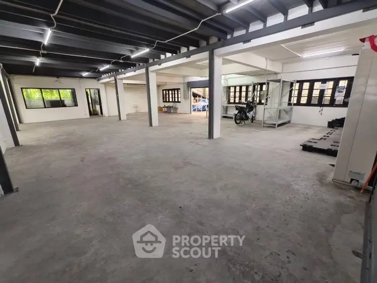 Spacious industrial-style open space with large windows and concrete flooring, ideal for versatile use.