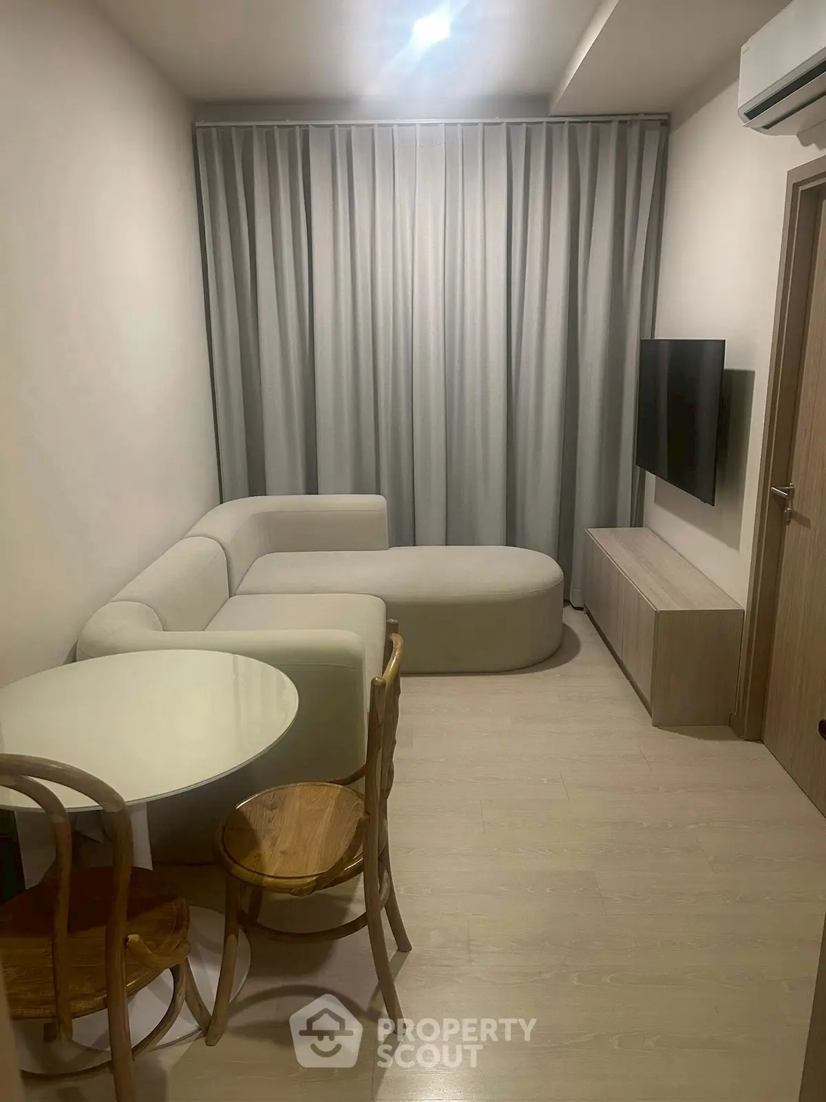 Cozy modern living room with stylish furniture and wall-mounted TV, perfect for relaxation and entertainment.