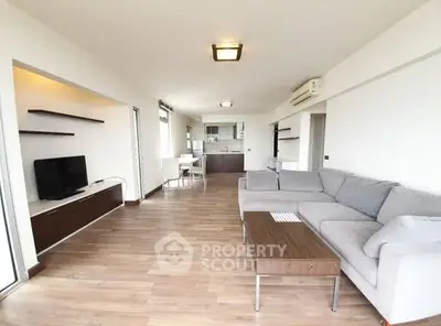 Spacious open-plan living room with modern furniture and sleek kitchen area.