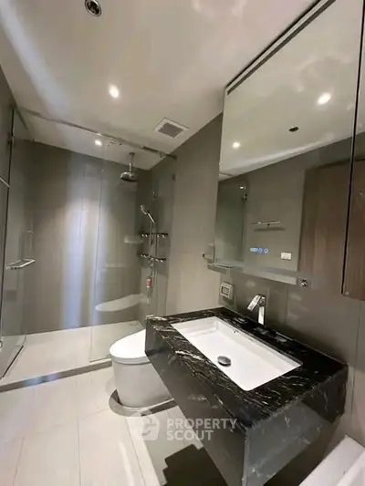 Modern bathroom with sleek design, featuring a glass shower and elegant black marble sink.