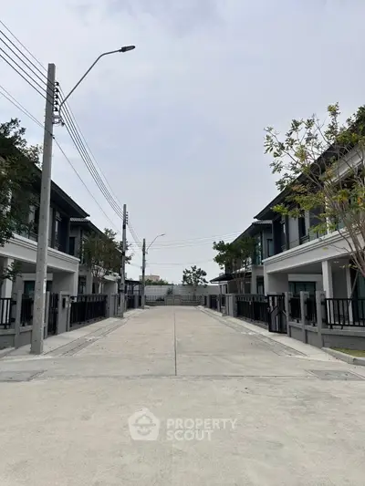 Modern residential street with contemporary townhouses and lush greenery.