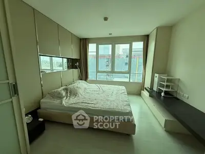 Spacious bedroom with large windows and modern decor in a high-rise apartment.
