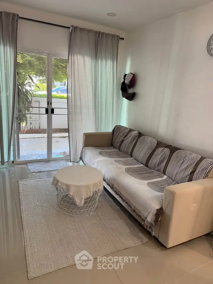 Cozy living room with modern sofa and natural light from large window, perfect for relaxation.