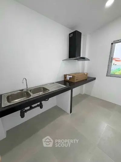 Modern kitchen with sleek black countertops and stainless steel sink, featuring a large window for natural light.