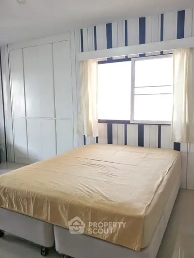 Cozy bedroom with striped wallpaper and natural light from window