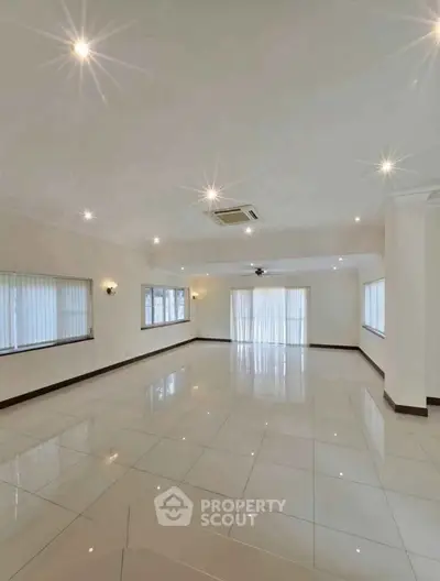 Spacious modern living room with large windows and glossy tiled floors.