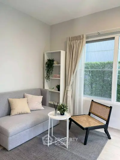 Chic living room with modern sofa, stylish chair, and natural light from large window.