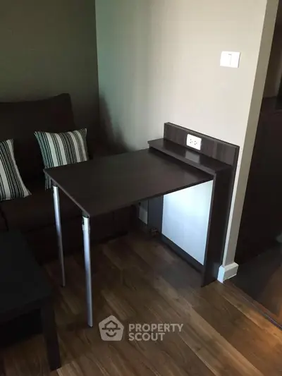 Compact living room with modern furniture and wooden flooring, featuring a versatile foldable table.