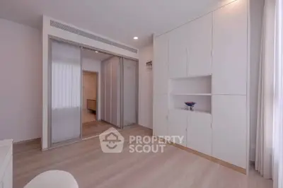 Spacious modern bedroom with sleek built-in storage and sliding closet doors.
