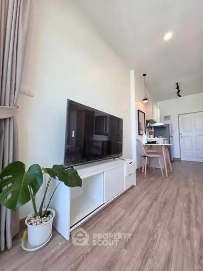 Modern living room with sleek TV stand, stylish dining area, and open kitchen layout.