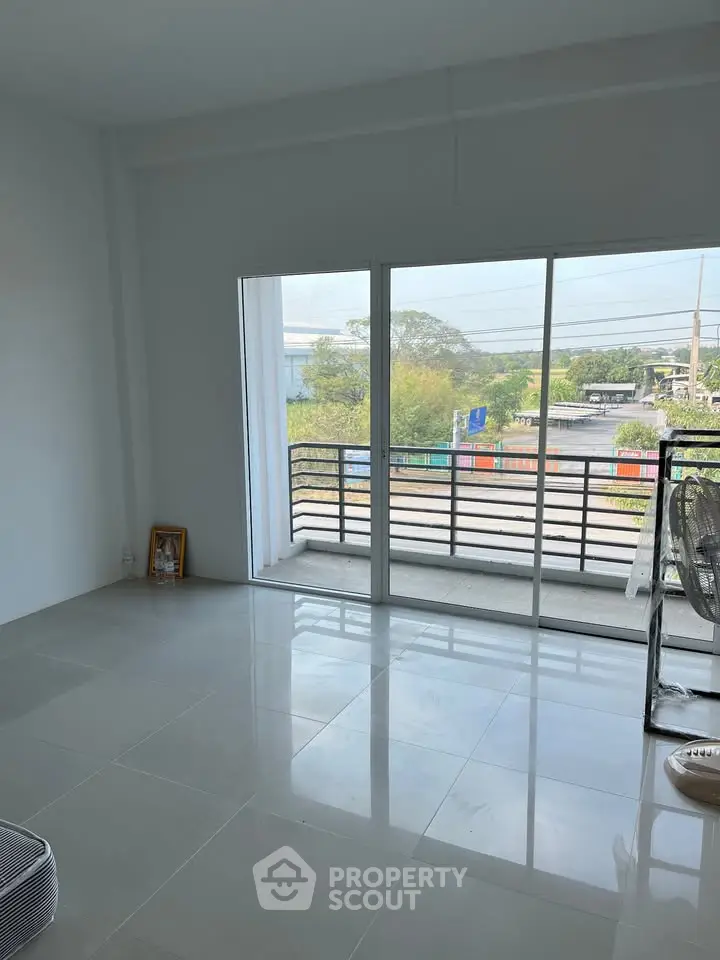Spacious living room with large windows and balcony offering scenic views, perfect for relaxation and entertaining.