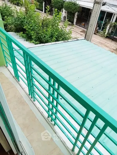 Charming balcony with vibrant green railing overlooking a serene neighborhood view.