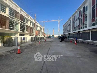 Modern townhouse complex with construction crane in background under clear blue sky.