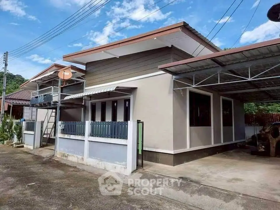Modern single-story house with carport and fenced yard under clear blue sky.