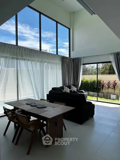 Spacious modern living room with large windows and garden view, perfect for relaxation.