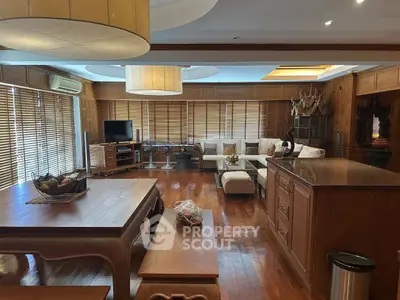 Spacious living room with wooden flooring and modern decor, featuring a cozy seating area and entertainment setup.
